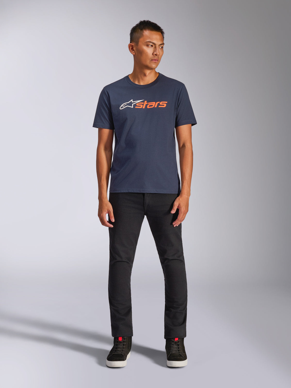 Alpinestars Blaze 2.0 CSF Tee, Short Sleeve T-Shirt, Navy Blue with White and Orange Astars Logo, worn with black pants and black sneakers, casual motorsport-inspired streetwear