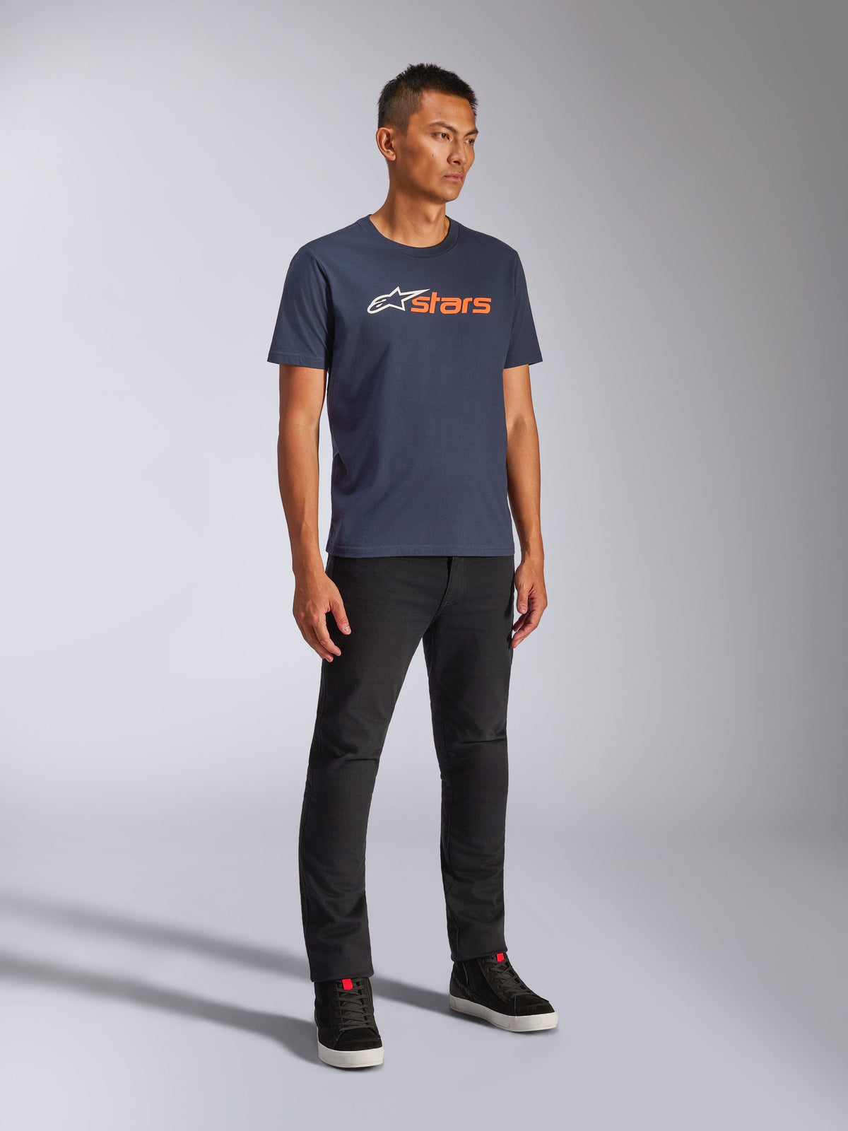 Alpinestars Blaze 2.0 CSF Tee, Short Sleeve T-Shirt, Navy Blue with White and Orange Blaze Logo, worn by model with black pants and sneakers, casual motorsport-inspired streetwear