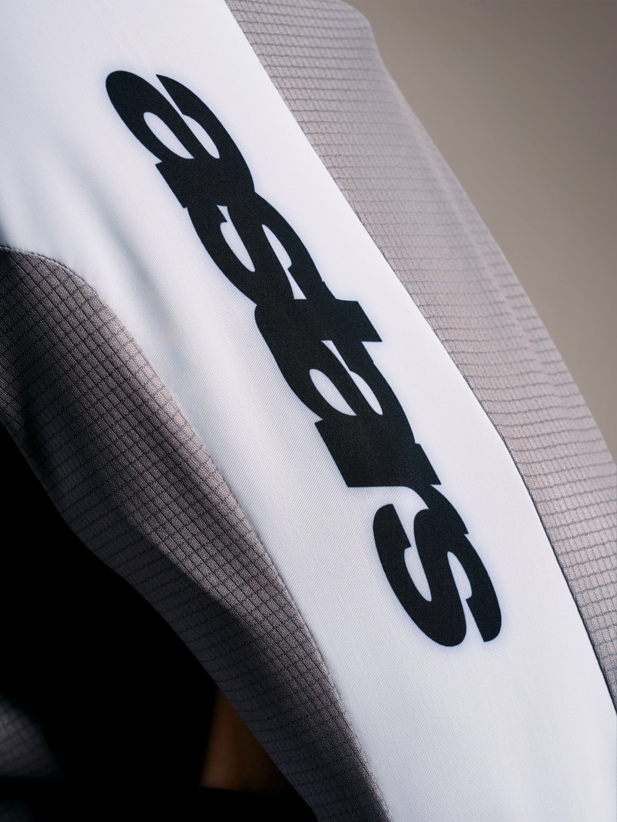 A-Supra Elite Jersey detail, Faded Gray micro-perforated fabric with black ASTARS logo on a white sleeve band.