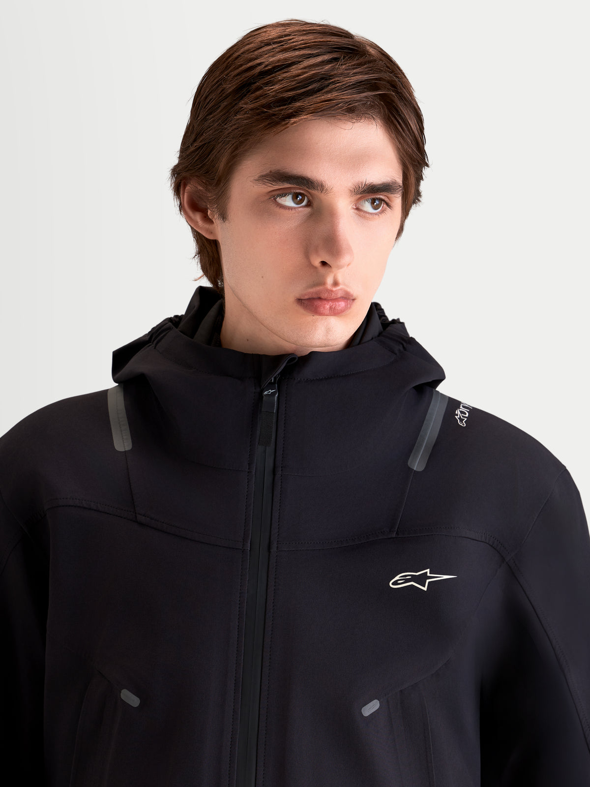 Alpinestars C-7 Drystar®XF Jacket, men's urban contemporary motorcycle jacket in black, close-up view on a model wearing the waterproof textile jacket with an integrated hood and reflective details.