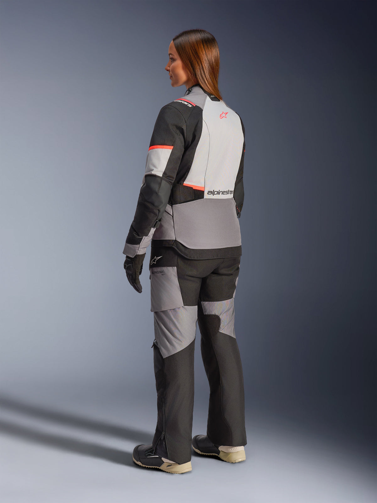 Alpinestars Stella Andes V4 Drystar® Jacket, women's adventure touring motorcycle jacket in dark gray, ice gray, and black with coral fluo accents, rear view on a model wearing matching gear.