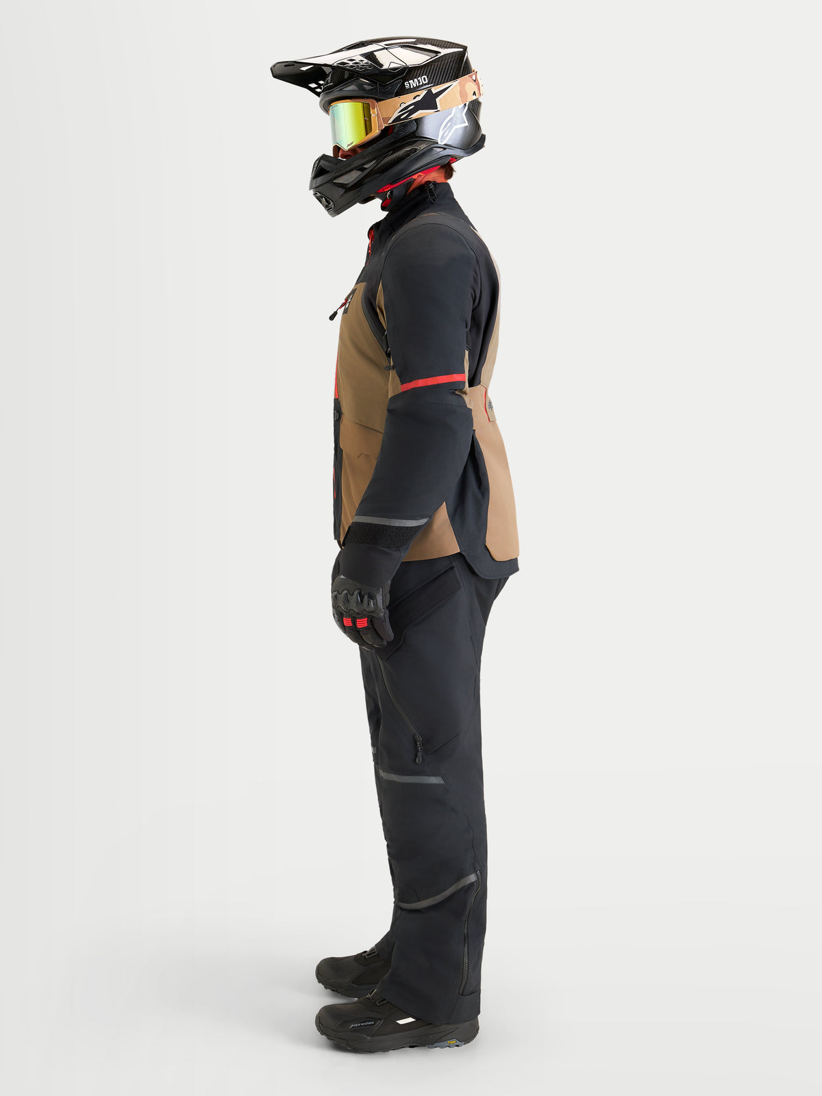 Alpinestars St-7 V2 2L Gore-Tex Gear Set, adventure touring motorcycle jacket and pants in black and brown, side profile view on a model wearing matching gear, helmet, goggles, and gloves, waterproof all-weather riding apparel