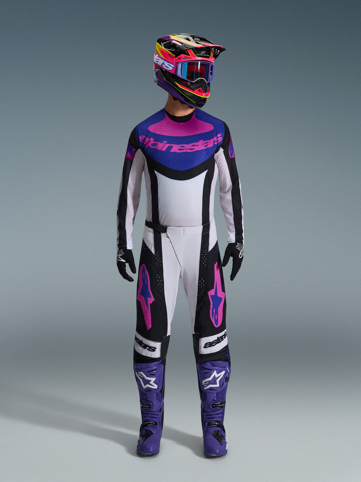 Alpinestars 2026 Techstar Knif Gear Set, Complete Motocross Outfit, White Black Purple and Pink, worn with a multi-colored helmet, blue goggles, purple boots, and black gloves, coordinated high-performance kit for off-road racing