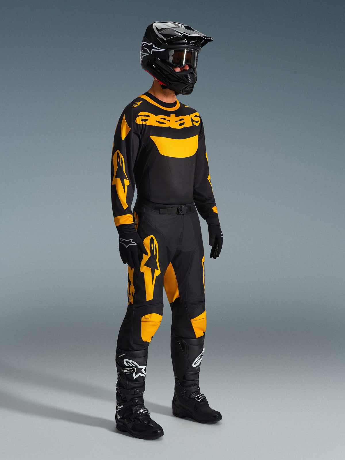 Motocross rider wearing the 2026 Racer Riway Jersey in Yellow and Black, complete racing gear set with matching pants, black helmet, gloves, and boots, designed for off-road performance with bold Alpinestars graphics.