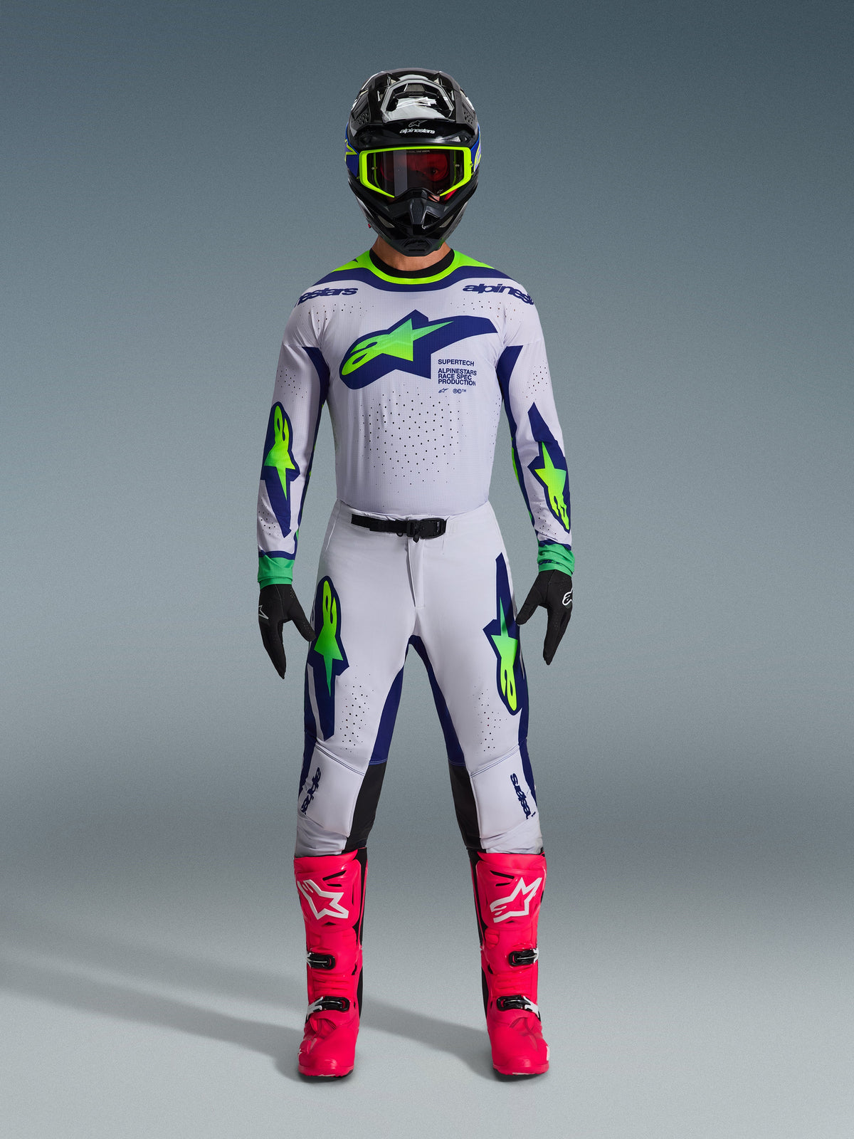 Motocross rider wearing the 2026 Supertech Vista Jersey in Light Gray Yellow Fluo Blue, complete with matching pants, bright pink boots, and a black helmet with neon accents, pro-level off-road racing gear.