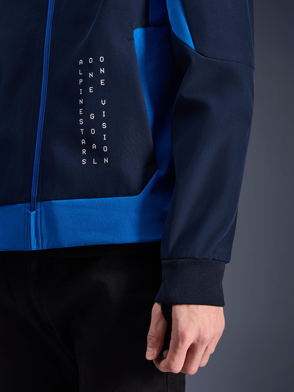 Alpinestars Radium Tech Hoodie, Urban Motorcycle Hoodie, Night Navy and Royal Blue, close-up detail showing side panel with white vertical text graphic, ribbed stretch cuff, and blue zipper closure