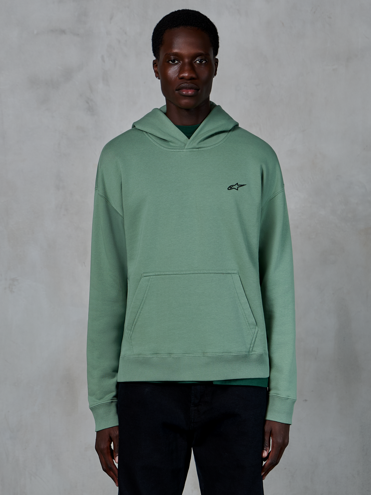 Alpinestars Essentials Ageless Hoodie, Cactus green, casual fleece hoodie with a stone-washed finish, features a small black star logo on the chest and a front pouch pocket, worn by a model in a clean lifestyle setting