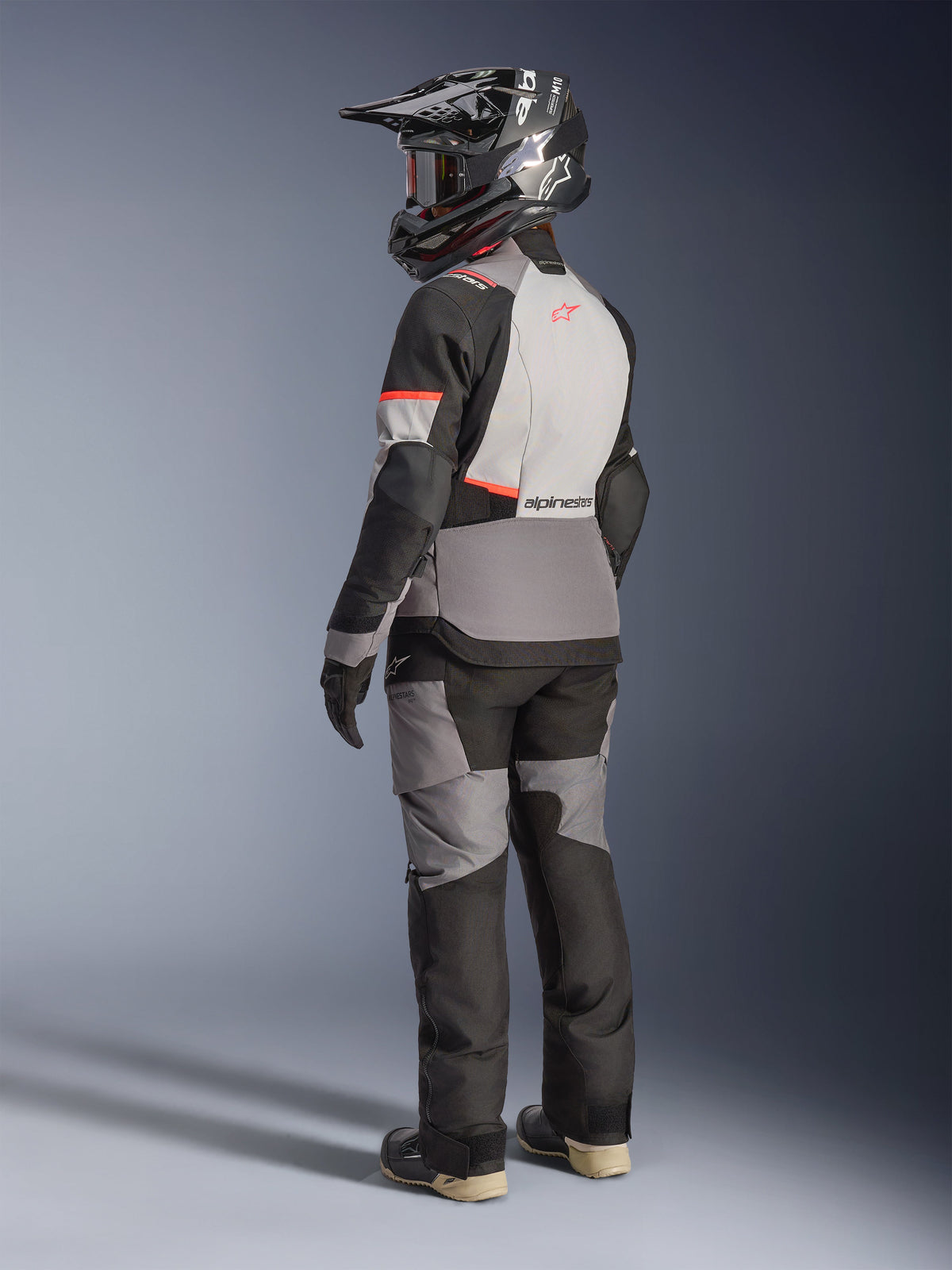 Alpinestars Stella Andes V4 Drystar® Jacket, women's adventure touring motorcycle jacket in dark gray, ice gray, black, and coral fluo, rear view on a model wearing matching gear and helmet.