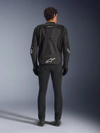 Alpinestars T-GP Air Jacket, Black, Rear view of a man wearing the textile motorcycle jacket, featuring mesh ventilation panels, an aerodynamic hump, and white Alpinestars logos on the lower back and elbows, worn with black riding pants and gloves
