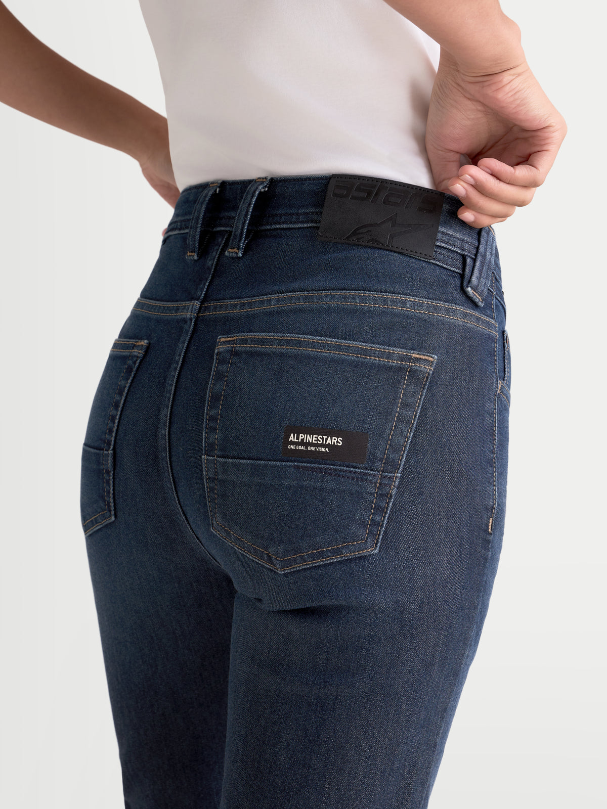 Alpinestars Stella Flex-AST 7 Denim Pants, women's motorcycle riding jeans in dark blue, rear view showing a model wearing the five-pocket chassis with a branded leather back patch and label detail.