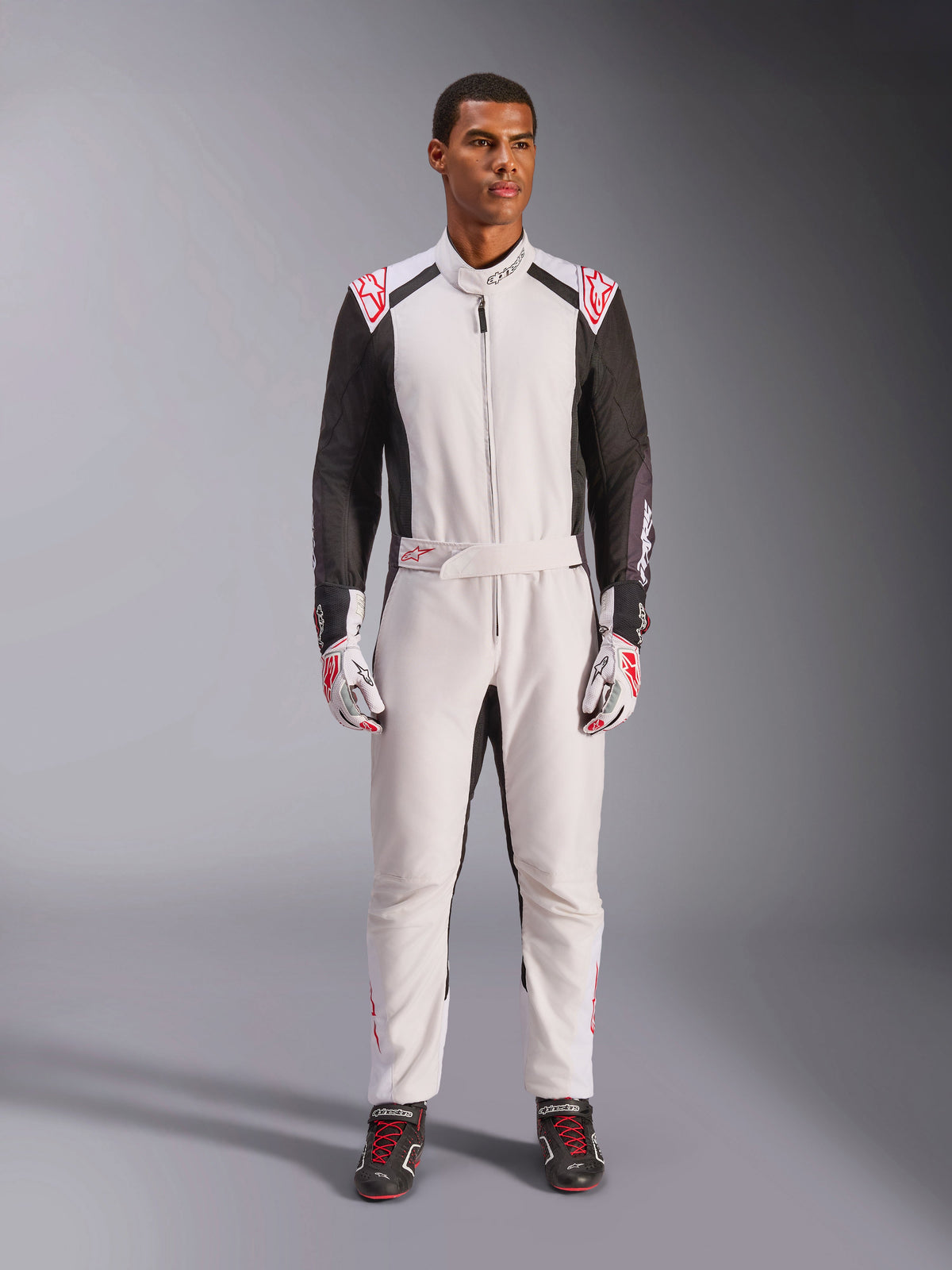 Alpinestars KMX-5 V3 Suit, one-piece karting suit, White Black and Bright Red, worn by a model with matching racing gloves and shoes, professional motorsport gear for competitive go-kart driving.