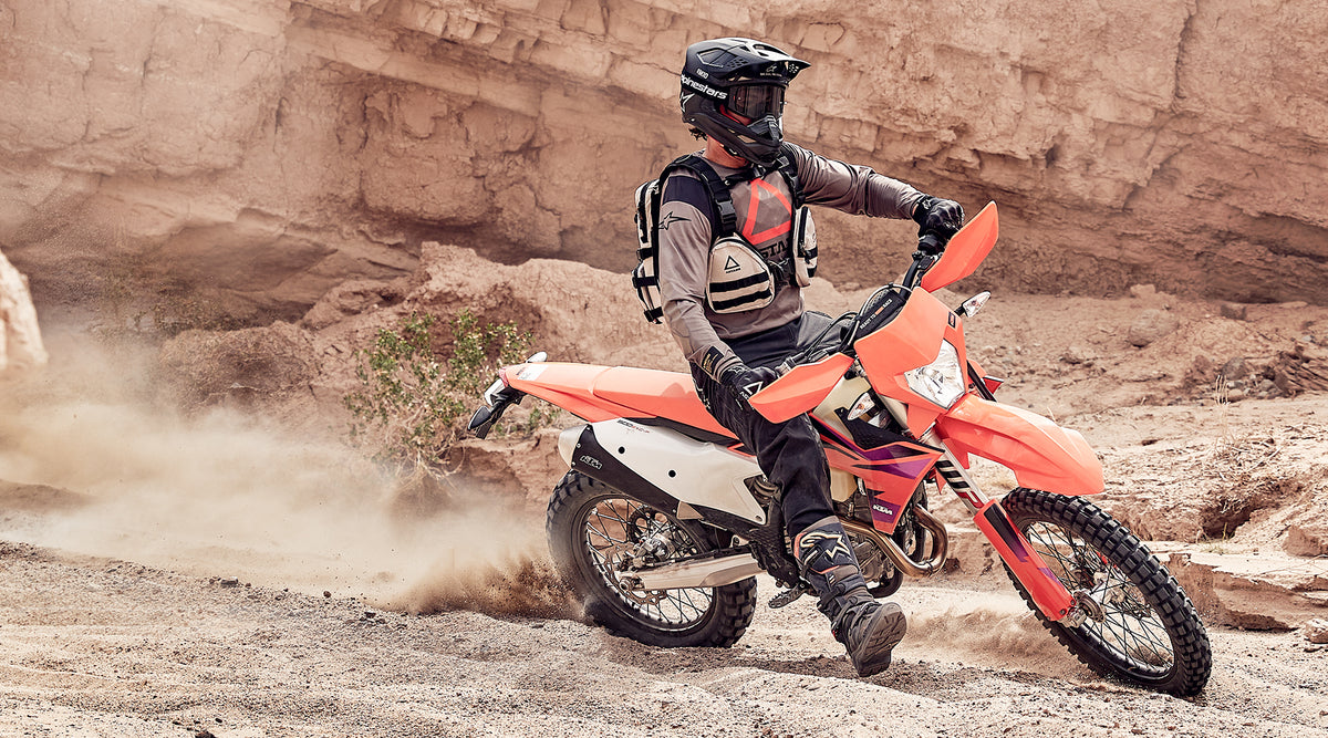Alpinestars Techdura Jersey and Tech 7 Enduro Boots, brown and black gear on an enduro rider on a bike in a dusty canyon.