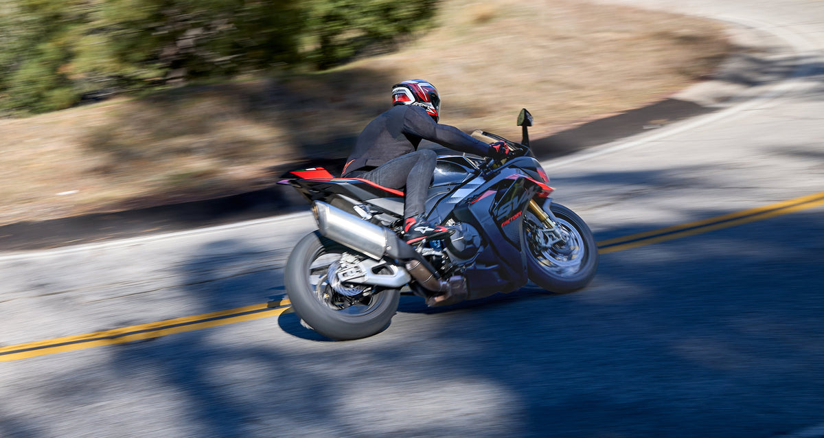 Alpinestars Celer Shoes, Black and Bright Red motorcycle riding shoes, worn by a rider on a sportbike leaning into a turn.