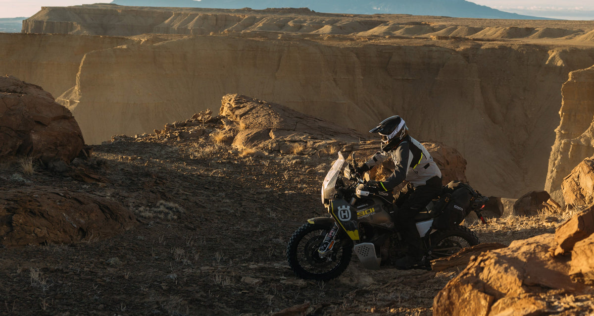 Alpinestars Cusco Drystar Jacket and Pants, gray and black adventure motorcycle gear, on a rider in a desert canyon.