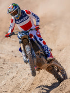 Alpinestars Limited Edition Techstar Fortitude Pants, Motocross Pants, Bright Red White and Blue, worn by a rider in action on a dirt track, featuring matching jersey and boots, performance-driven off-road racing gear.