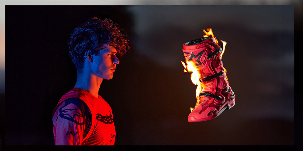 Alpinestars Supertech Ember Gear, Motocross, Red Fluo and Black, Tech 10 boot in flames beside a rider in dramatic lighting.