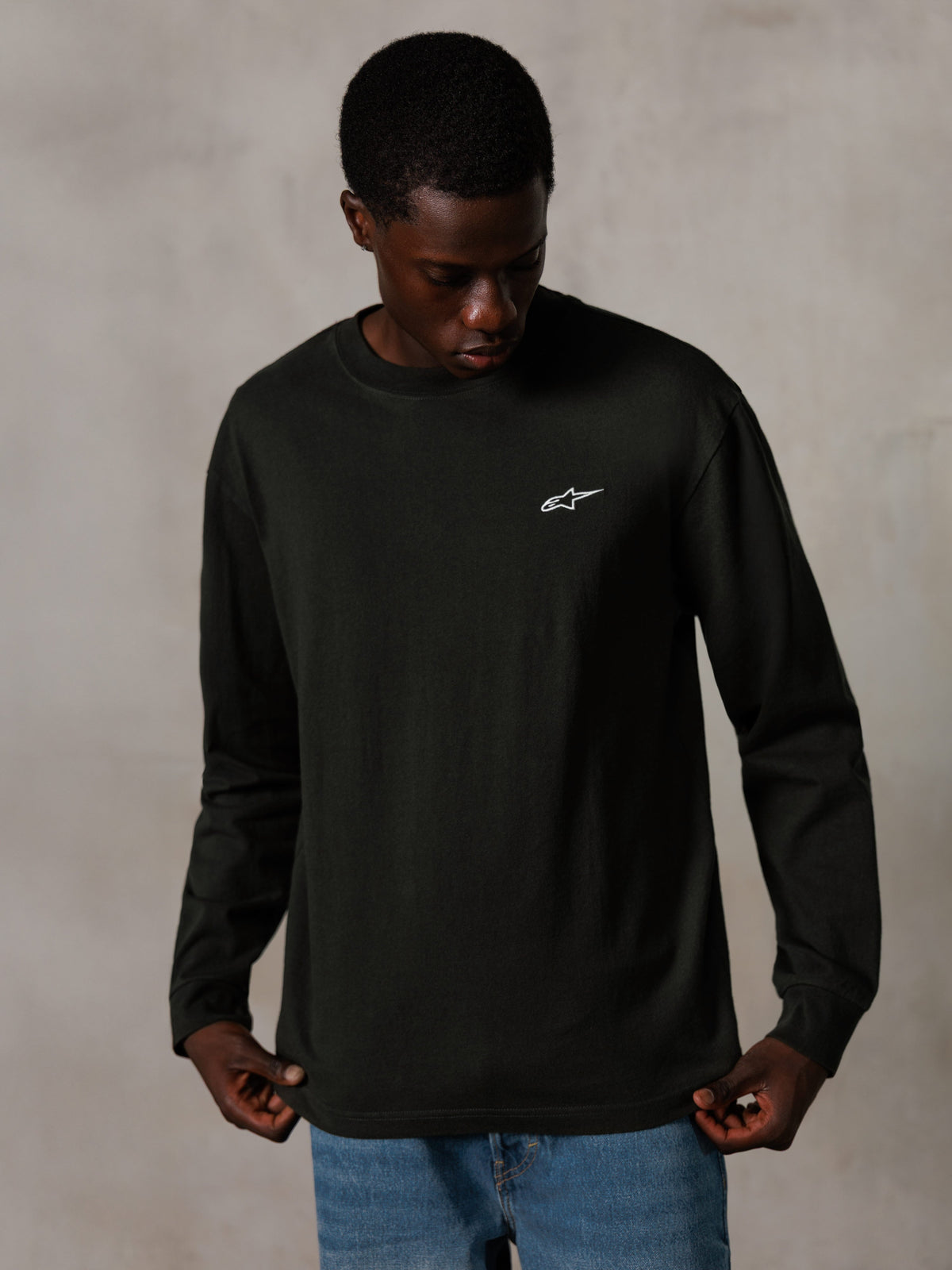 Alpinestars Essentials Ageless LS Tee, Long-Sleeve T-Shirt, Off Black, featuring a small white logo on the chest, worn by a model with blue jeans, casual lifestyle streetwear