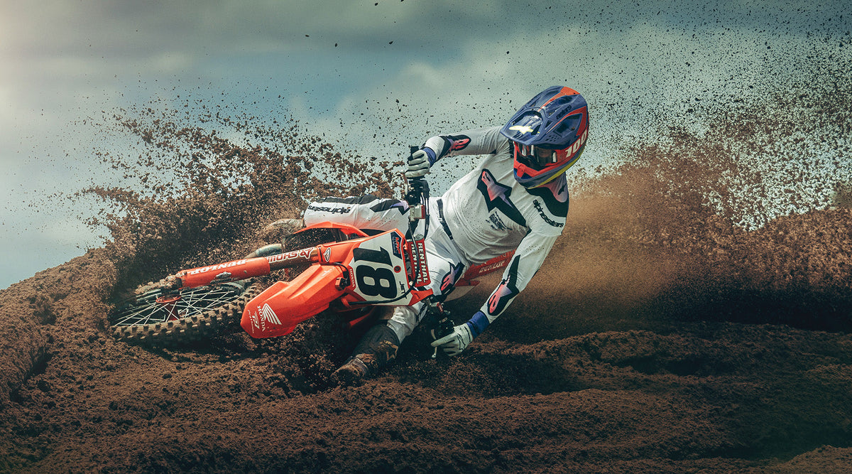 Alpinestars Supertech M10 Jett Lawrence R01 Helmet, Purple and Pink, worn by a motocross rider cornering through the dirt.