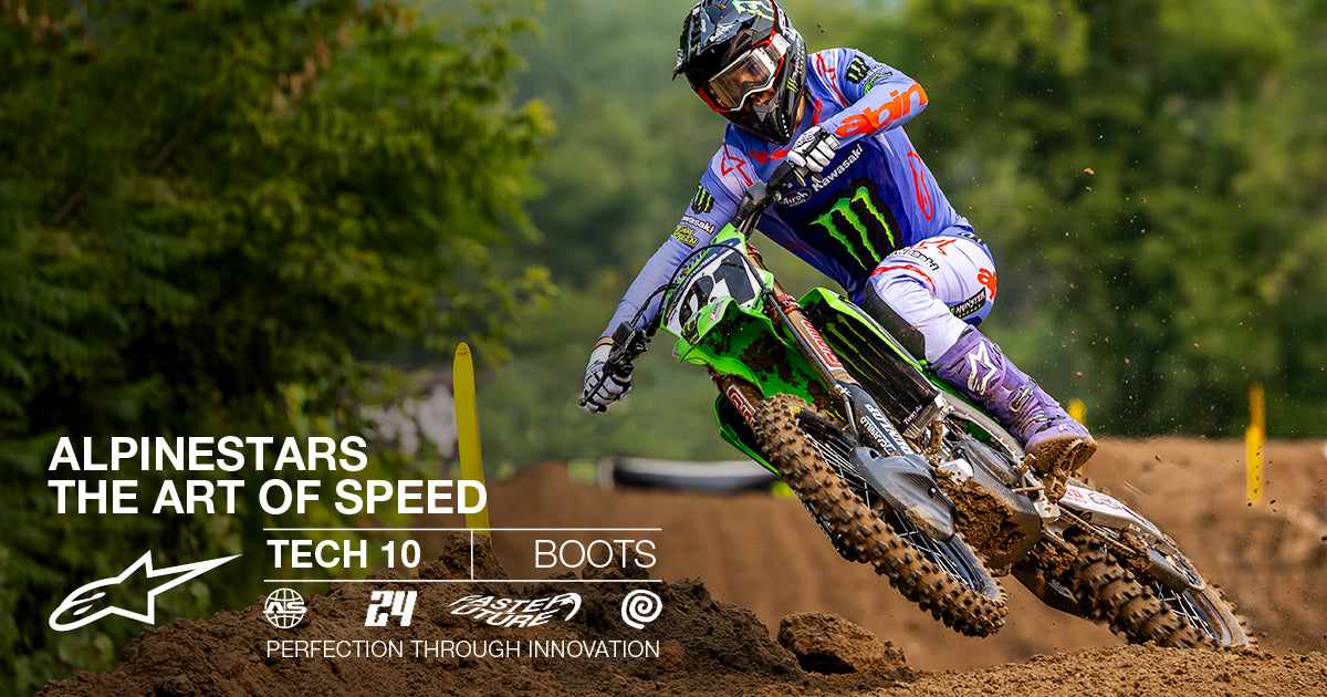 Alpinestars Tech 10 Boots, purple motocross racing boots, worn by a rider leaning into a turn on a dirt track.