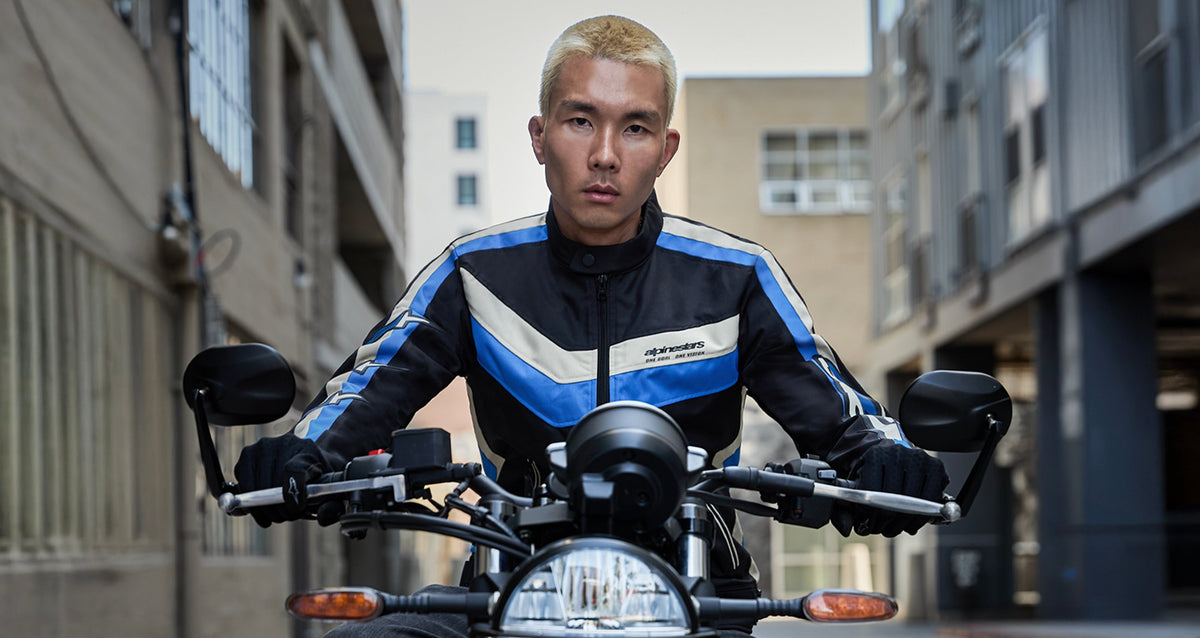 Alpinestars T-Dyno Water Resistant Jacket, black and blue textile motorcycle jacket, worn by a man on a motorcycle in the city.
