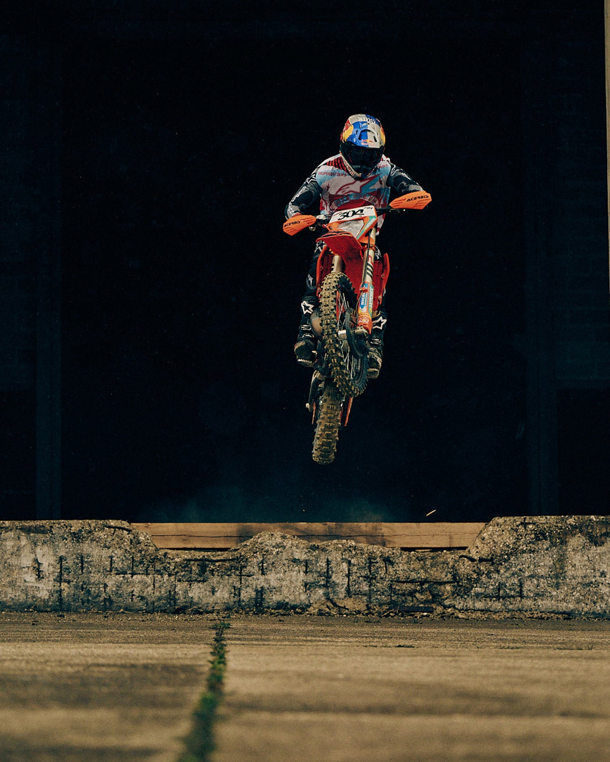 Alpinestars Limited Edition S-M7 Beast Coast Helmet and Visor, light gray and hot orange, worn during a motocross jump.