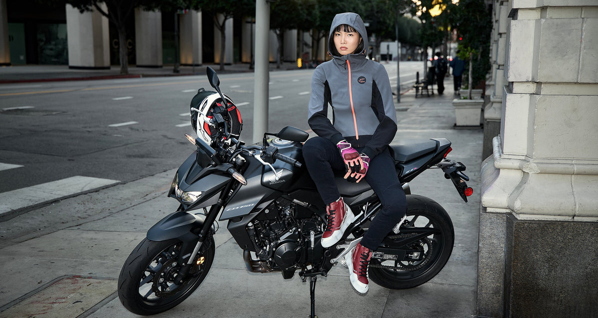 Alpinestars Stella Radium Tech Hoodie, women's deep gray and black urban motorcycle jacket on-model with a street bike.